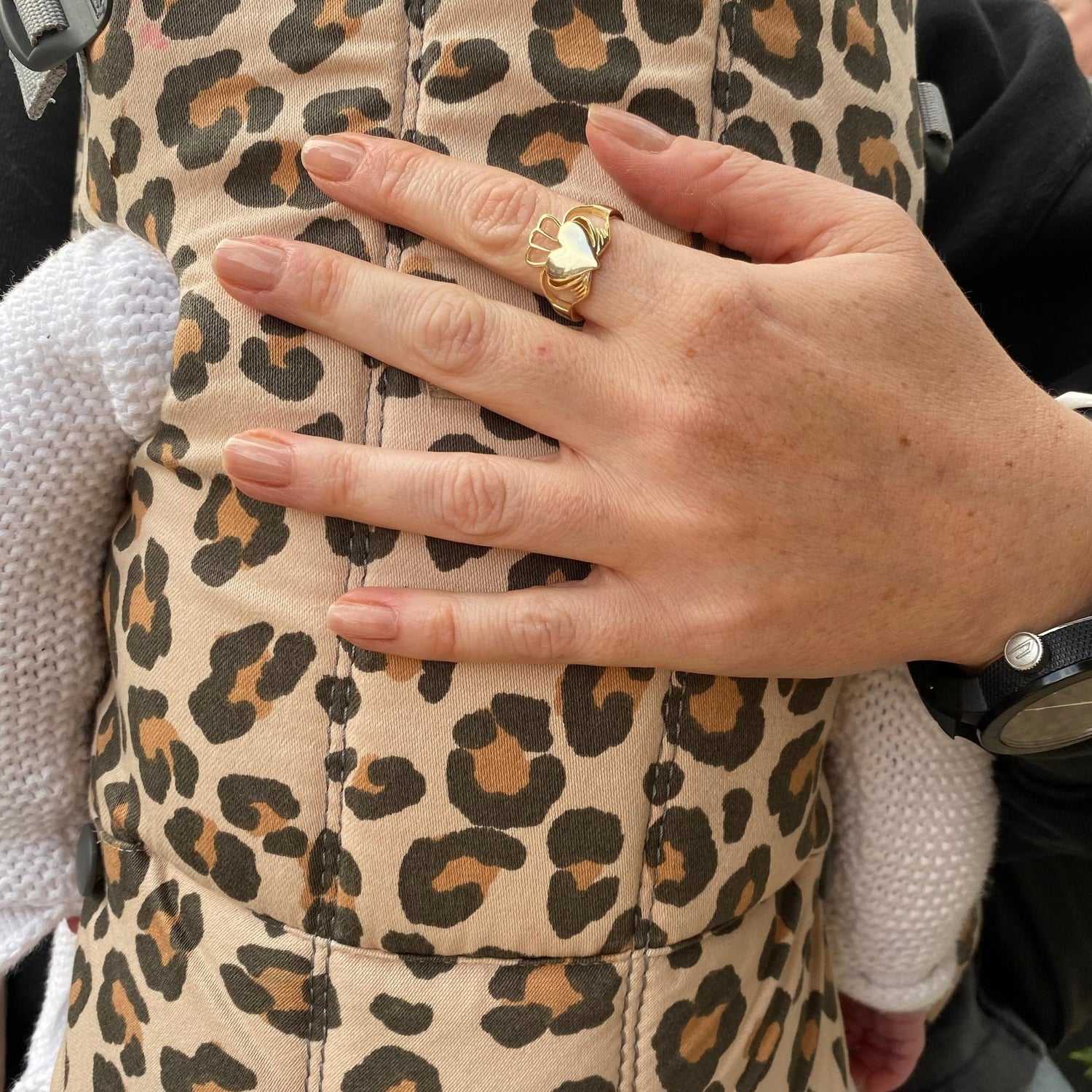 Model wearing Have My Heart Gold Claddagh Ring holding a baby in a sling 
