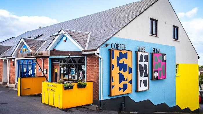 Small shops with brick and white walls, painted blue facade, yellow counters, and a sign reading COFFEE